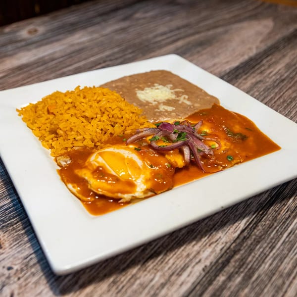 Huevos Rancheros with rice and refried beans on a white plate at Pancho Villa Mexican Restaurant.