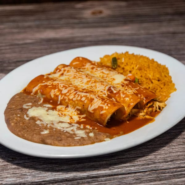 Three cheesy enchiladas with red sauce, refried beans, and Mexican rice on a white plate.
